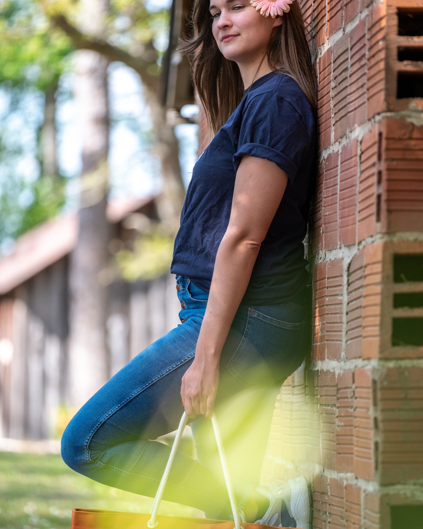 Woman carrying a patterned handbag beside a weathered brick wall