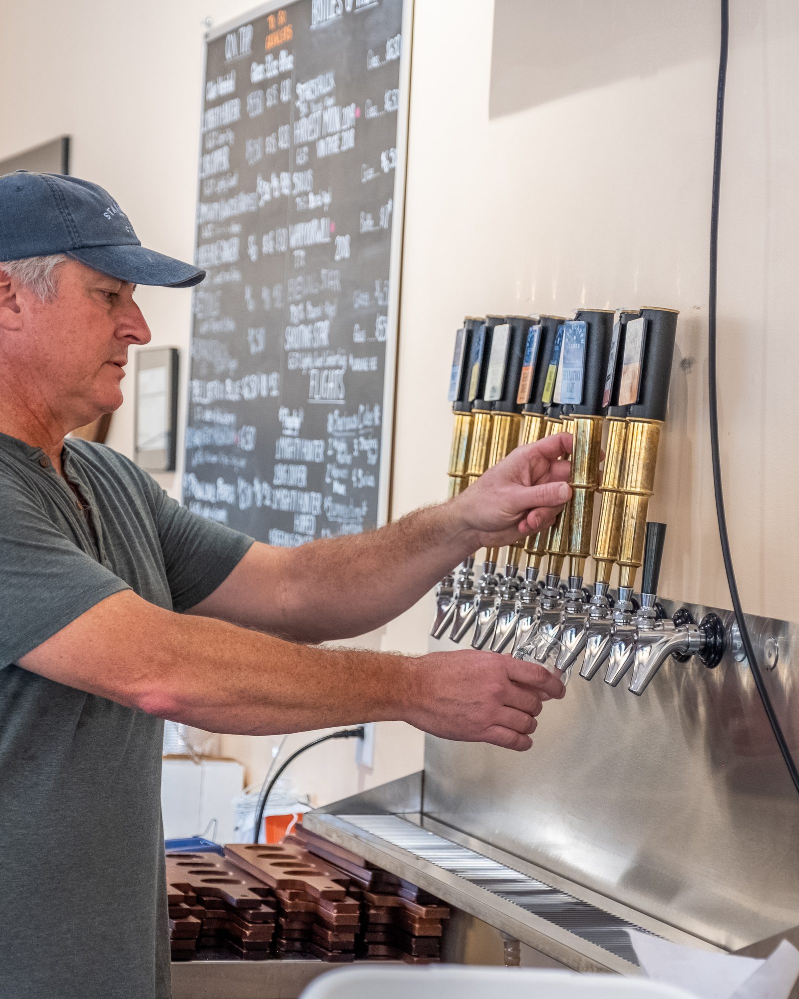 Cidermaker drawing a glass from a row of taps