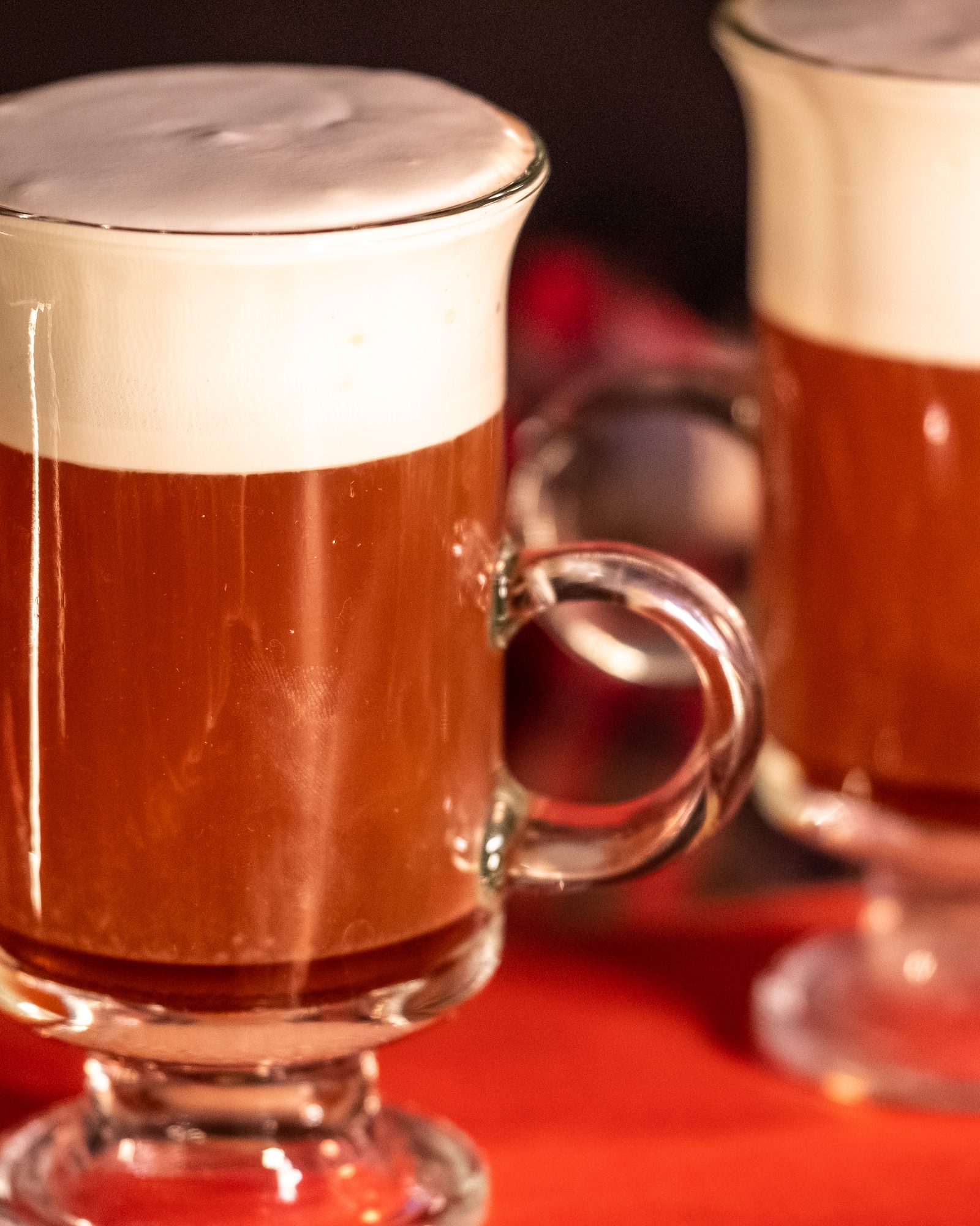 Two layered Irish coffees in glass mugs with rich cream tops