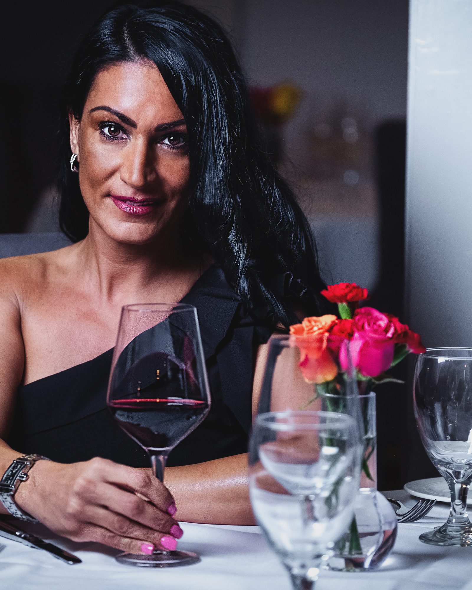 Woman seated at an elegantly set restaurant table holding a wine glass