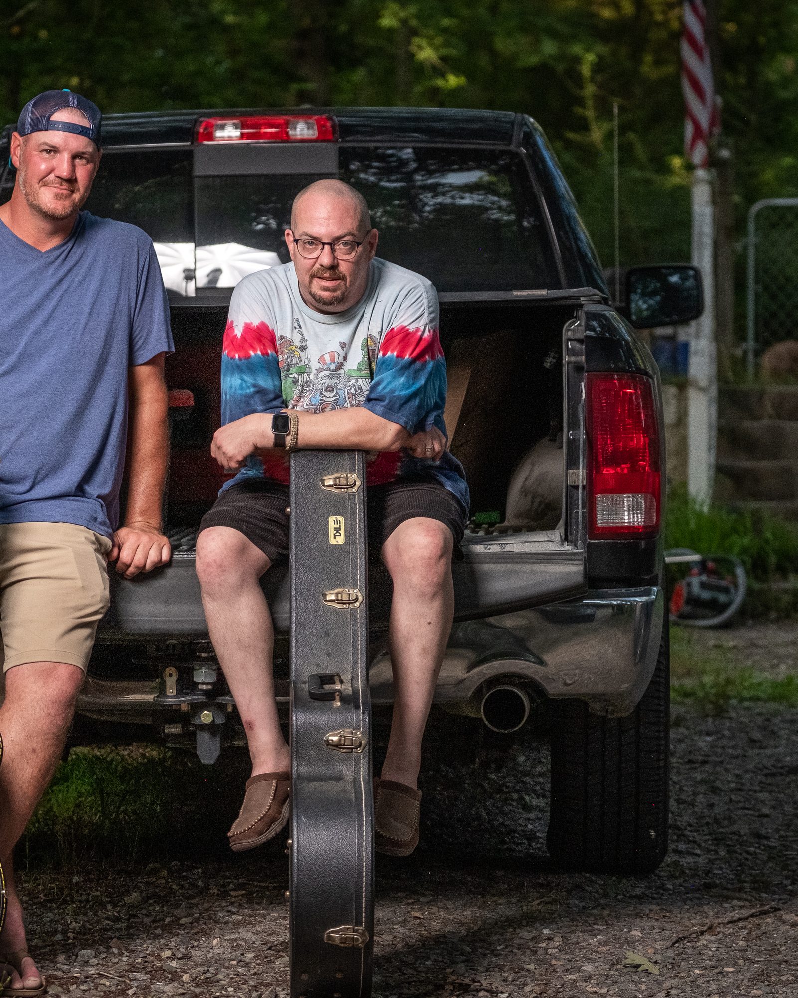 Two musicians standing beside a pickup truck with their instrument cases
