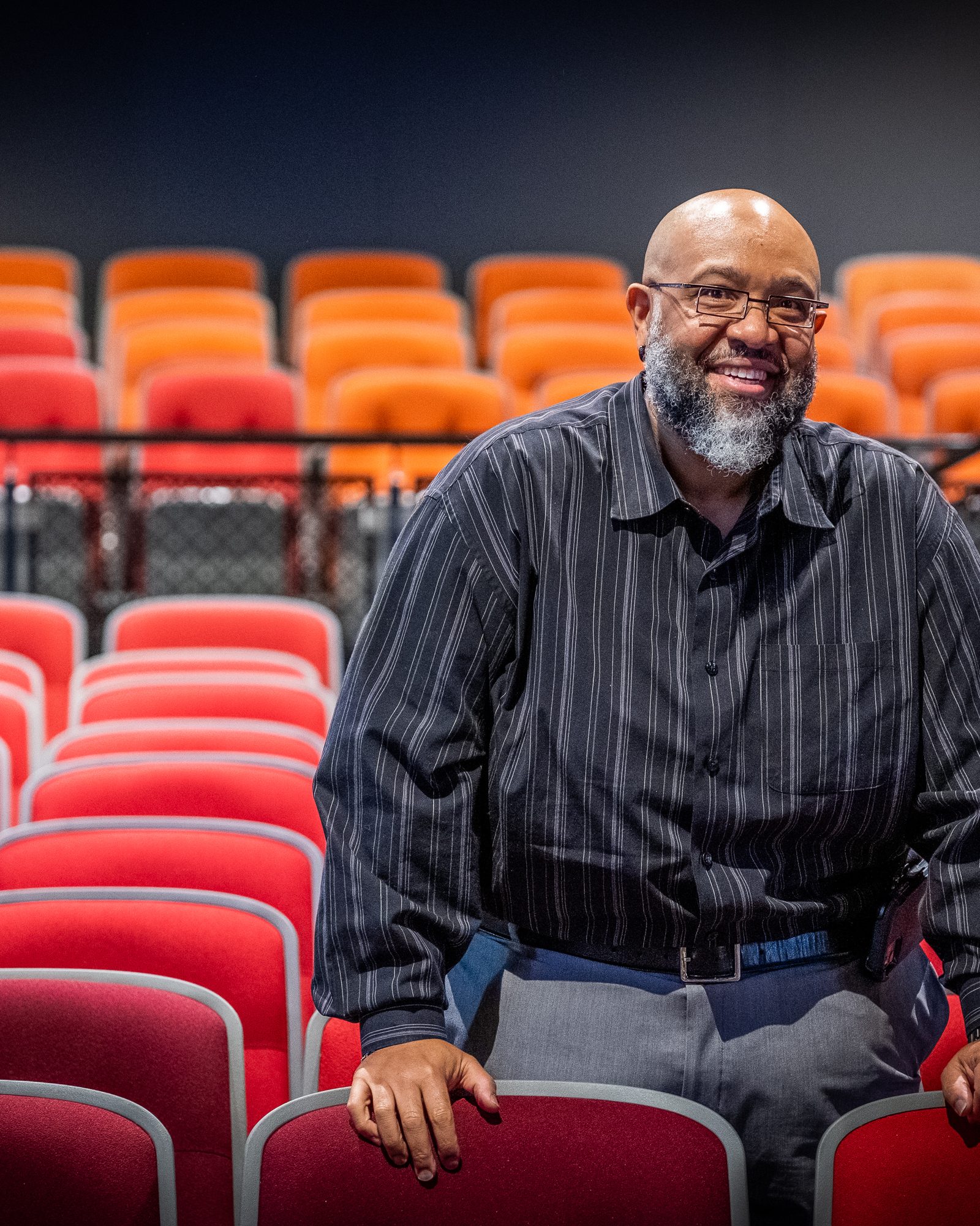 Smiling man standing among vivid red and orange theatre seats