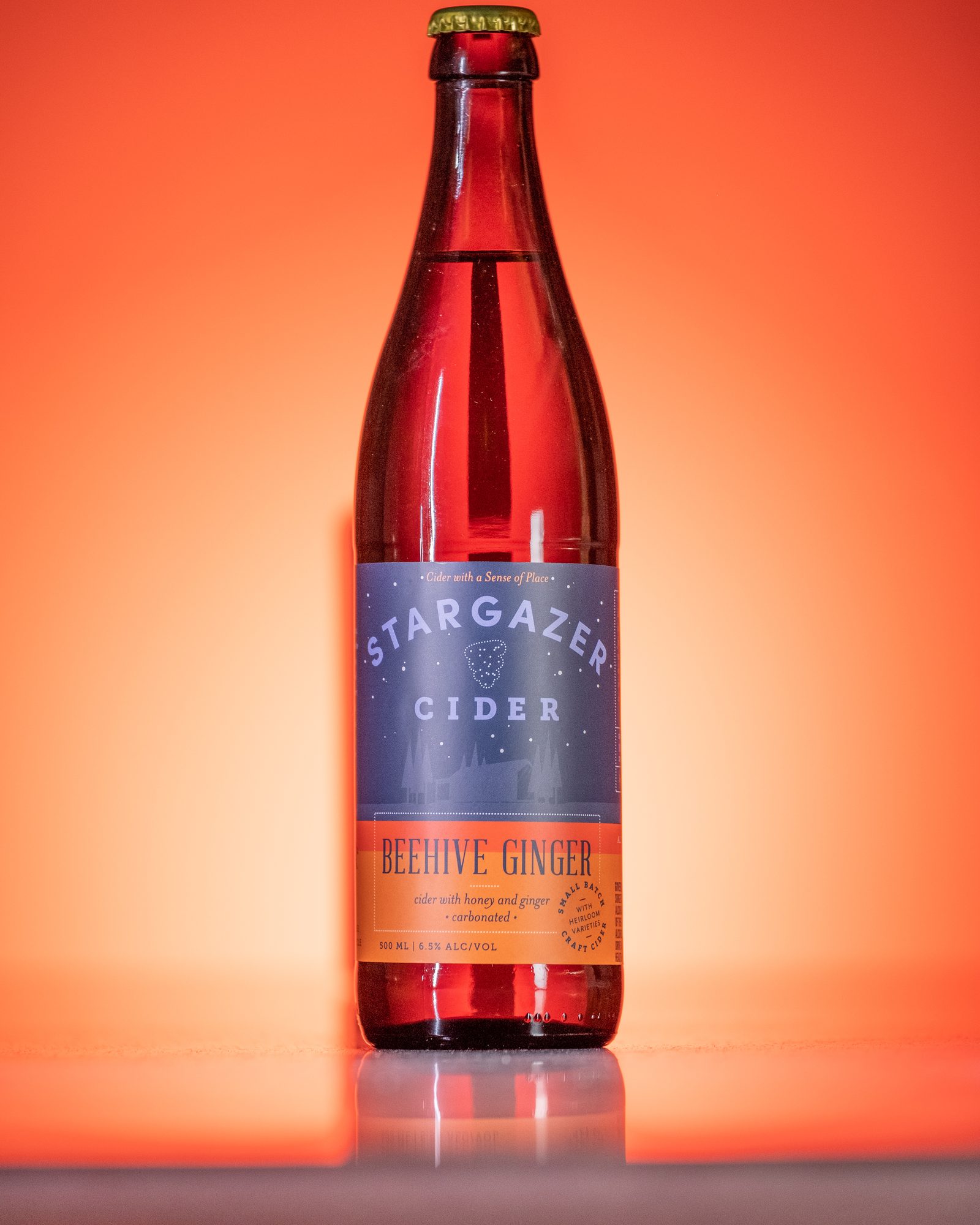 Single cider bottle photographed against a luminous red background